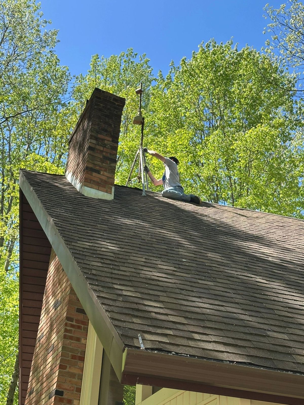 Old antenna being removed from the chimney of an A-frame roof