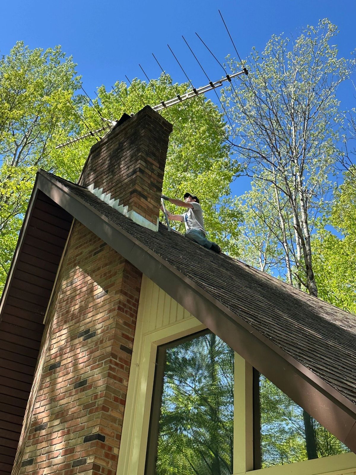 Working on the roof of an A-frame home to take down an old TV antenna, Canadian Lakes