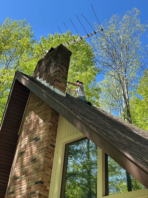 Working on the roof of an A-frame home to take down an old TV antenna, Canadian Lakes