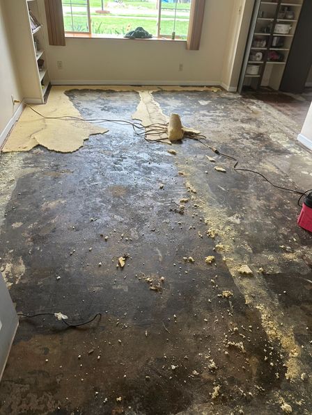 Concrete floor with old adhesive and flooring residue being scraped before new flooring